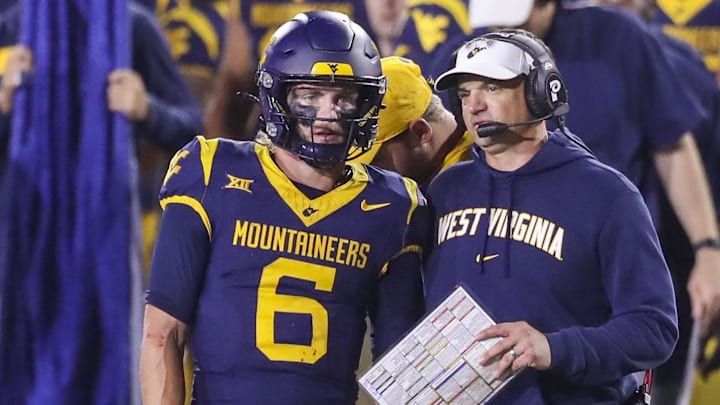 Oct 19, 2024; Morgantown, West Virginia, USA; West Virginia Mountaineers head coach Neal Brown talks with quarterback Garrett Greene (6) before a play during the second quarter against the Kansas State Wildcats at Mountaineer Field at Milan Puskar Stadium. Mandatory Credit: Ben Queen-Imagn Images