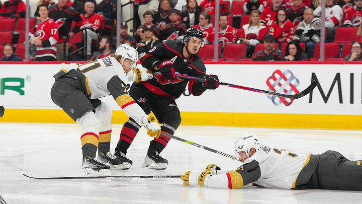 Oct 28, 2025; Raleigh, North Carolina, USA; Carolina Hurricanes center Sebastian Aho (20) gets the shot away against Vegas Golden Knights center William Karlsson (71) during the third period at Lenovo Center. Mandatory Credit: James Guillory-Imagn Images