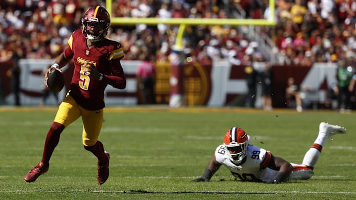 Oct 6, 2024; Landover, Maryland, USA; Washington Commanders quarterback Jayden Daniels (5) runs with the ball past Cleveland Browns defensive end Za'Darius Smith (99) during the second quarter at NorthWest Stadium. Mandatory Credit: Geoff Burke-Imagn Images