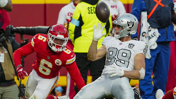 Nov 29, 2024; Kansas City, Missouri, USA; Las Vegas Raiders tight end Brock Bowers (89) tosses the ball after scoring a touchdown against Kansas City Chiefs safety Bryan Cook (6) during the second half at GEHA Field at Arrowhead Stadium. Mandatory Credit: Jay Biggerstaff-Imagn Images