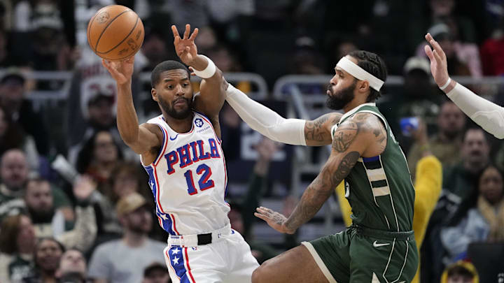 Feb 9, 2025; Milwaukee, Wisconsin, USA;  Philadelphia 76ers guard Jared Butler (12) passes the ball around dMilwaukee Bucks guard Gary Trent Jr. (5) during the fourth quarter at Fiserv Forum. Mandatory Credit: Jeff Hanisch-Imagn Images