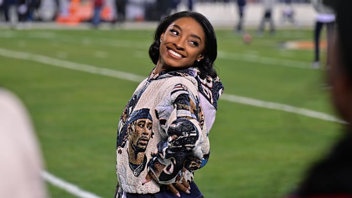 Dec 26, 2024; Chicago, Illinois, USA; United States gymnast Simone Biles poses for a photo on the sidelines before the game between the Chicago Bears and the Seattle Seahawks at Soldier Field. 