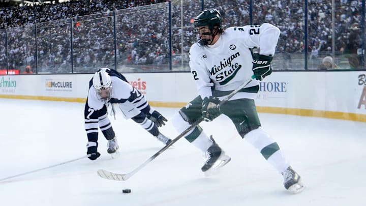 Jan 31, 2026; State College, PA, USA; Michigan State Spartans forward Porter Martone (22) moves the puck against Penn State Nittany Lions defenseman Jackson Smith (7) during the second period at Beaver Stadium. Mandatory Credit: Matthew O'Haren-Imagn Images