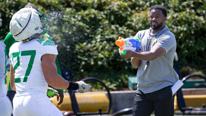 Oregon running backs coach Ra'Shaad Samples sprays running back Jayden Limar during practice with the Ducks. Oregon running backs coach Ra'Shaad Samples sprays running back Jayden Limar during practice with the Ducks.