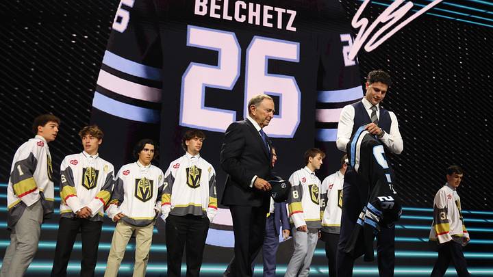 Jun 26, 2026; Buffalo, New York, USA; Ethan Belchetz reacts beside NHL commissioner Gary Bettman after being selected with the seventeenth pick in the first round of the 2026 NHL Draft by the Utah Mammoth at KeyBank Center. Mandatory Credit: Timothy T. Ludwig-Imagn Images