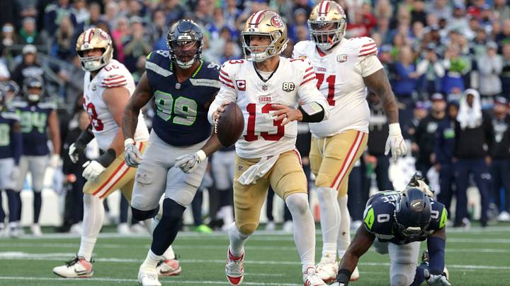 Oct 11, 2026; Seattle, Washington, USA;  San Francisco 49ers quarterback Brock Purdy (13) scrambles and looks to throw a pass against Seattle Seahawks defensive tackle Leonard Williams (99) and linebacker DeMarcus Lawrence (0) during the second half at Lumen Field.  Mandatory Credit: Joe Nicholson-Imagn Images