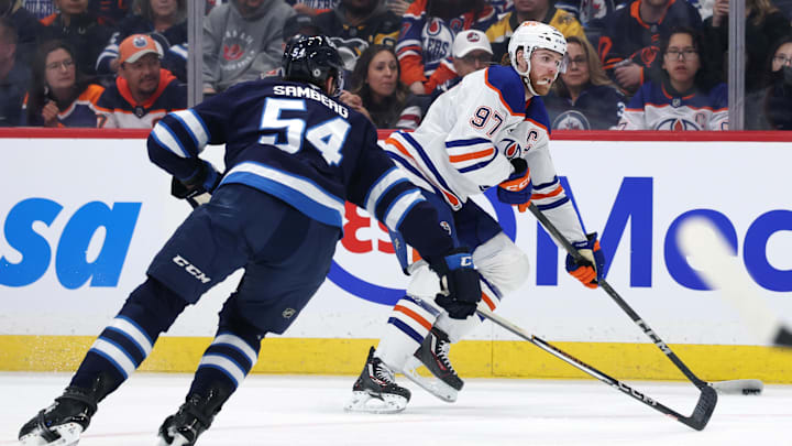 Apr 13, 2025; Winnipeg, Manitoba, CAN; Edmonton Oilers center Connor McDavid (97) eludes Winnipeg Jets defenseman Dylan Samberg (54) in the first period at Canada Life Centre. Mandatory Credit: James Carey Lauder-Imagn Images