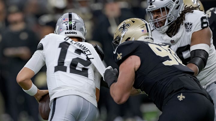 Dec 29, 2024; New Orleans, Louisiana, USA;  New Orleans Saints defensive tackle Bryan Bresee (90) takes off the jersey of Las Vegas Raiders quarterback Aidan O'Connell (12) for a sack during the first half at Caesars Superdome. Mandatory Credit: Matthew Hinton-Imagn Images