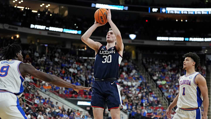 Mar 23, 2025; Raleigh, NC, USA; Connecticut Huskies forward Liam McNeeley (30) drives to the basket during the first half against Florida Gators center Rueben Chinyelu (9) in the second round of the NCAA Tournament at Lenovo Center. Mandatory Credit: Bob Donnan-Imagn Images