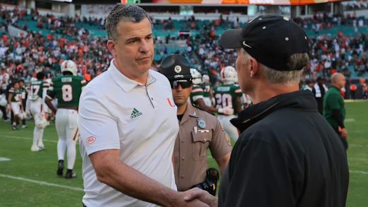 Nov 23, 2024; Miami Gardens, Florida, USA; Miami Hurricanes head coach Mario Cristobal shakes hands with Wake Forest Demon Deacons head coach Dave Clawson after the game at Hard Rock Stadium. Mandatory Credit: Sam Navarro-Imagn Images