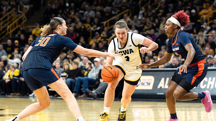 Iowa guard Taylor Stremlow (1) dribbles between Illinois forward Cearah Parchment (30) and Illinois guard Jasmine Brown-Hagger (8) Feb. 26, 2026 at Carver-Hawkeye Arena in Iowa City, Iowa.