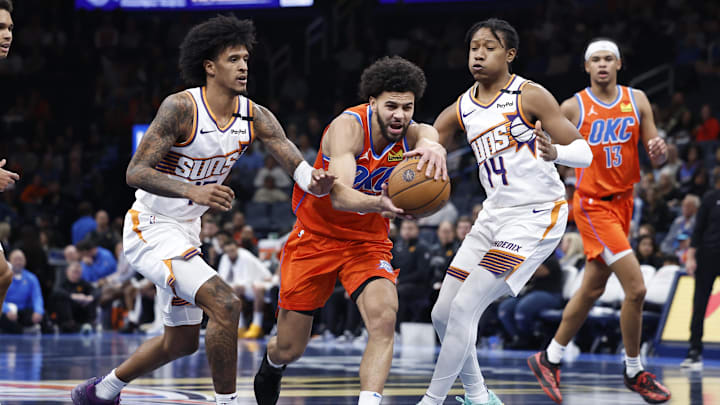 Nov 15, 2024; Oklahoma City, Oklahoma, USA; Oklahoma City Thunder guard Ajay Mitchell (25) drives to the basket between Phoenix Suns forward Jalen Bridges (15) and guard TyTy Washington Jr. (14)during the fourth quarter at Paycom Center. Mandatory Credit: Alonzo Adams-Imagn Images Nov 15, 2024; Oklahoma City, Oklahoma, USA; Oklahoma City Thunder guard Ajay Mitchell (25) drives to the basket between Phoenix Suns forward Jalen Bridges (15) and guard TyTy Washington Jr. (14)during the fourth quarter at Paycom Center. Mandatory Credit: Alonzo Adams-Imagn Images