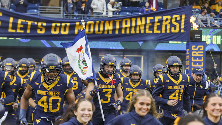 Nov 23, 2024; Morgantown, West Virginia, USA; West Virginia Mountaineers wide receiver Hudson Clement (3) carries the West Virginia state flag as he leads his team onto the field before a game against the UCF Knights at Mountaineer Field at Milan Puskar Stadium. Mandatory Credit: Ben Queen-Imagn Images
