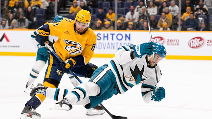 Jan 21, 2025; Nashville, Tennessee, USA;  Nashville Predators defenseman Adam Wilsby (83) and San Jose Sharks defenseman Jan Rutta (84) battle for the puck during the second period at Bridgestone Arena. Mandatory Credit: Steve Roberts-Imagn Images