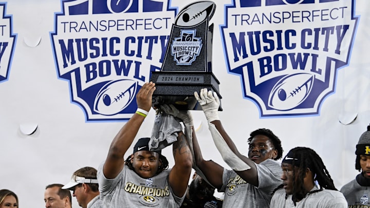 Several Missouri Tigers players hold up the TransPerfect Music City Bowl trophy, after a game versus the Iowa Hawkeyes last season.