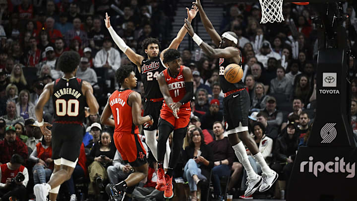 Apr 12, 2024; Portland, Oregon, USA; Houston Rockets guard Aaron Holiday (0) passes the ball during the second half against Portland Trail Blazers forward Justin Minaya (24) and center Duop Reath (26) at Moda Center. Mandatory Credit: Troy Wayrynen-USA TODAY Sports Apr 12, 2024; Portland, Oregon, USA; Houston Rockets guard Aaron Holiday (0) passes the ball during the second half against Portland Trail Blazers forward Justin Minaya (24) and center Duop Reath (26) at Moda Center. Mandatory Credit: Troy Wayrynen-USA TODAY Sports