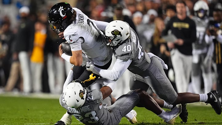 Oct 26, 2024; Boulder, Colorado, USA; Colorado Buffaloes defensive end Taje McCoy (40) and safety Carter Stoutmire (23) tackle Cincinnati Bearcats quarterback Brendan Sorsby (2) in the fourth quarter at Folsom Field. Mandatory Credit: Ron Chenoy-Imagn Images Oct 26, 2024; Boulder, Colorado, USA; Colorado Buffaloes defensive end Taje McCoy (40) and safety Carter Stoutmire (23) tackle Cincinnati Bearcats quarterback Brendan Sorsby (2) in the fourth quarter at Folsom Field. Mandatory Credit: Ron Chenoy-Imagn Images