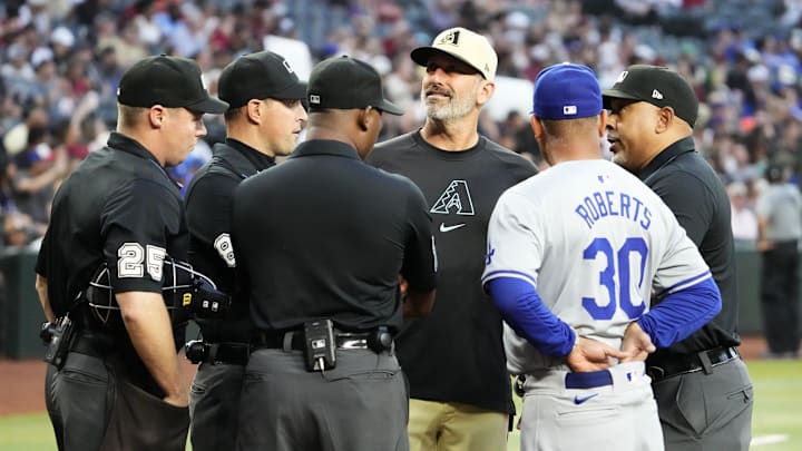Arizona Diamondbacks manager Torey Lovullo (17) talks to the umpires with Los Angeles Dodgers manager Dave Roberts (30) as bees swarm on the home plate net delaying the start of the game at Chase Field in Phoenix on April 30, 2024.