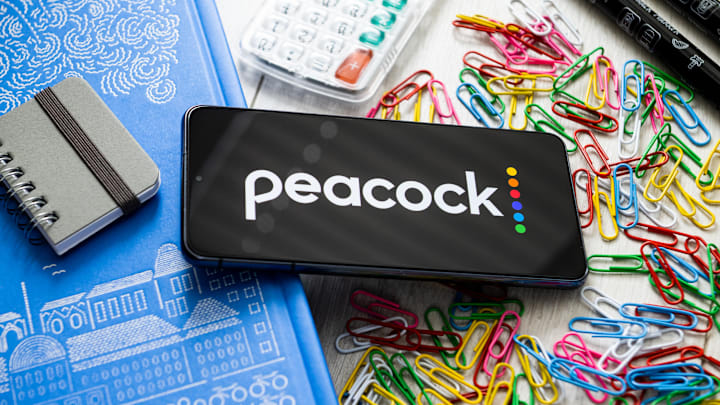 In this photo illustration a Peacock logo seen displayed on...