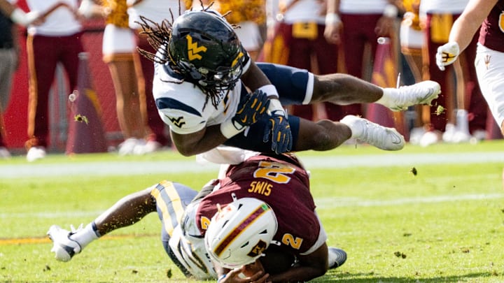 West Virginia Mountaineers Fred Perry (5) jumps over Arizona State Sun Devils Jeff Sims (2) and West Virginia Mountaineers Jordan Walker (4) during a game at Mountain America Stadium in Tempe on Nov. 15, 2025.