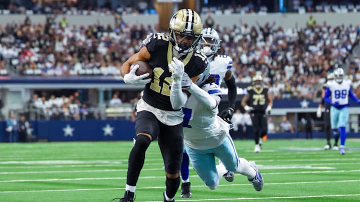 Sep 15, 2024; Arlington, Texas, USA;  New Orleans Saints wide receiver Chris Olave (12) runs with the ball as Dallas Cowboys cornerback Trevon Diggs (7) defends during the first quarter at AT&T Stadium. Mandatory Credit: Kevin Jairaj-Imagn Images