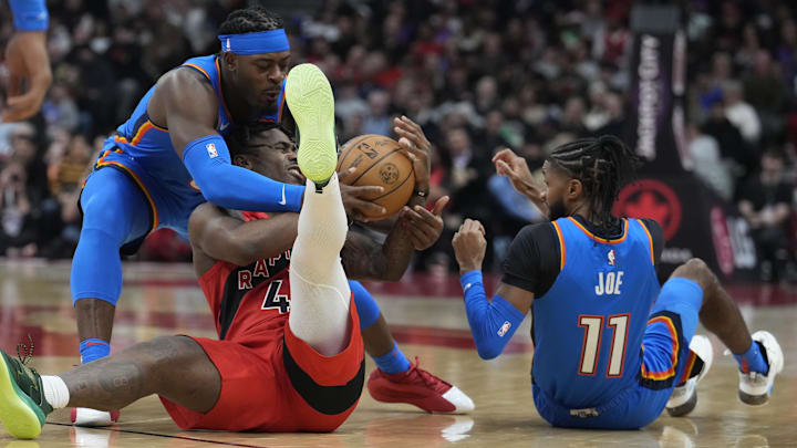 Dec 5, 2024; Toronto, Ontario, CAN;  Toronto Raptors guard Davion Mitchell (45) battles with Oklahoma City Thunder guard Luguentz Dort (5) and guard Isaiah Joe (11) for the ball during the first half at Scotiabank Arena. Mandatory Credit: John E. Sokolowski-Imagn Images