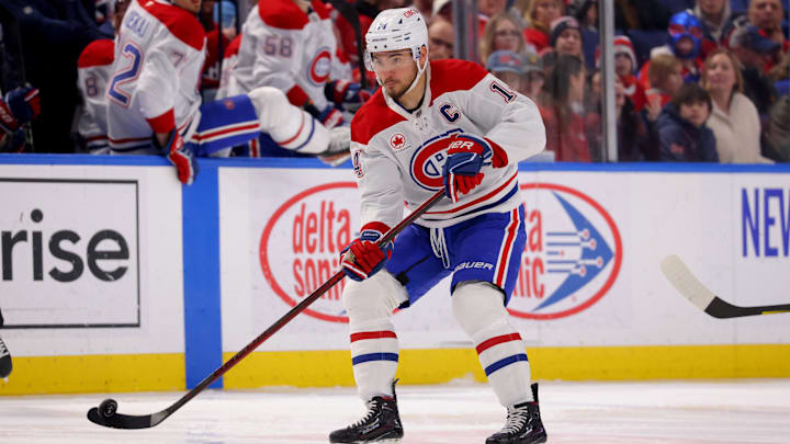 Mar 1, 2025; Buffalo, New York, USA;  Montreal Canadiens center Nick Suzuki (14) flips the puck up ice during the first period against the Buffalo Sabres at KeyBank Center. Mandatory Credit: Timothy T. Ludwig-Imagn Images