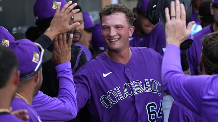 Colorado Rockies first baseman T.J. Rumfield (64) celebrates with teammates after hitting a solo home run. 