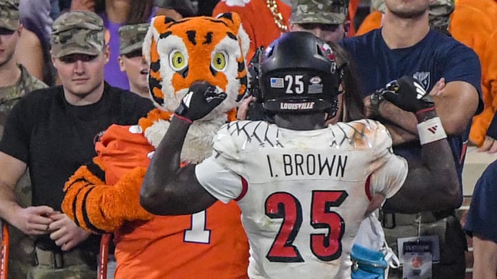 Nov 2, 2024; Clemson, South Carolina, USA; Louisville Cardinals running back Isaac Brown (25) flexes his muscles in front of the Clemson Tigers Tiger mascot after scoring in the fourth quarter at Memorial Stadium. Mandatory Credit: Ken Ruinard-Imagn Images Nov 2, 2024; Clemson, South Carolina, USA; Louisville Cardinals running back Isaac Brown (25) flexes his muscles in front of the Clemson Tigers Tiger mascot after scoring in the fourth quarter at Memorial Stadium. Mandatory Credit: Ken Ruinard-Imagn Images