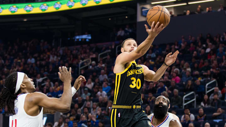 Feb 14, 2024; San Francisco, California, USA; Golden State Warriors guard Stephen Curry (30) lays up the ball in front of LA Clippers guard Brandon Boston Jr. (4) and guard James Harden (1) during the first half at Chase Center. Mandatory Credit: John Hefti-Imagn Images