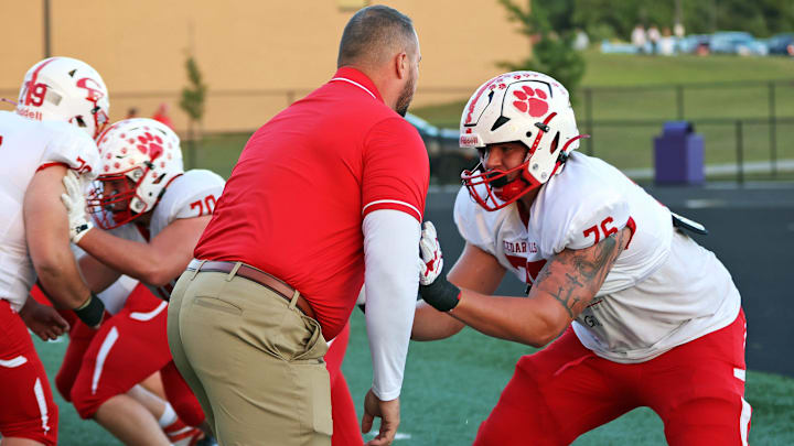 Cedar Falls senior lineman and ISU recruit Will Tompkins (76) warms up with his coach Ross Pierschbacher before the Cedar Falls Tigers compete against the Johnston Dragons on Friday, September 6, 2024, in Johnston.
