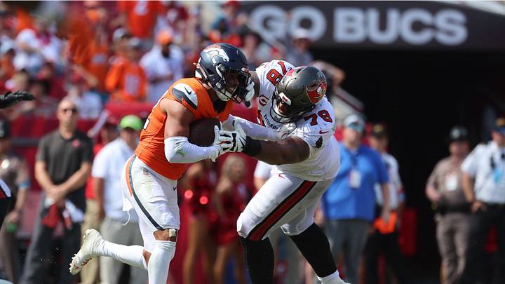 Sep 22, 2024; Tampa, Florida, USA; Denver Broncos safety Brandon Jones (22) picks up a fumble recovery as Tampa Bay Buccaneers offensive tackle Tristan Wirfs (78) attempts to defend during the second half at Raymond James Stadium. Mandatory Credit: Kim Klement Neitzel-Imagn Images