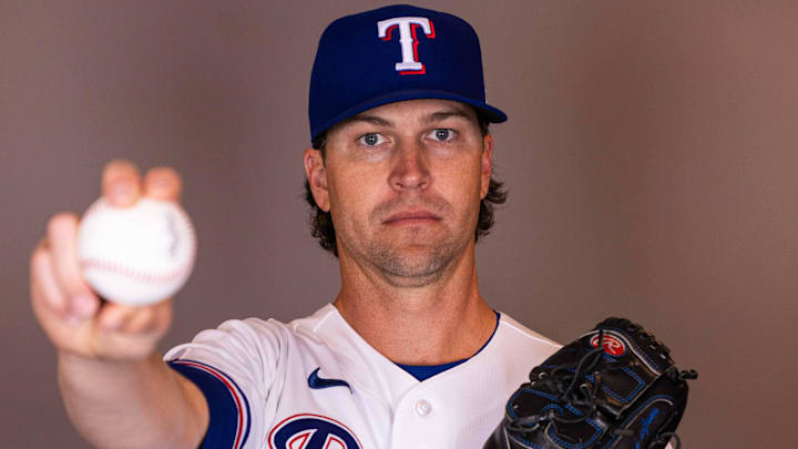 Texas Rangers pitcher Jacob deGrom holds a baseball while posing for a photo.