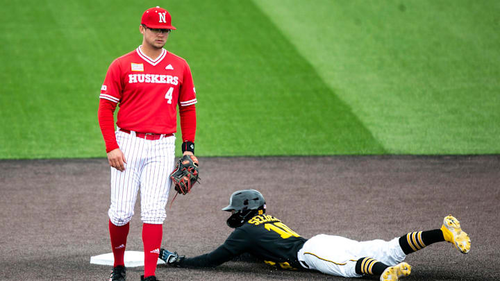 Nebraska's second baseman, Max Anderson, stands at second base as the Iowa Hawkeyes runner slides into second. 