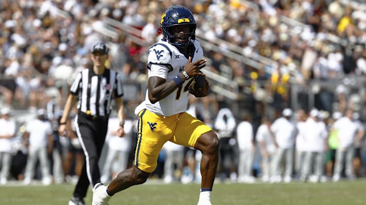 Oct 18, 2025; Orlando, Florida, USA;  West Virginia Mountaineers quarterback Khalil Wilkins (14) rushes for a first half touchdown against the Central Florida Knights at Acrisure Bounce House. Mandatory Credit: Russell Lansford-Imagn Images
