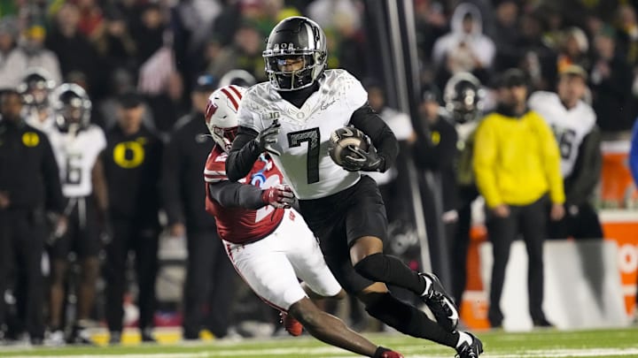 Nov 16, 2024; Madison, Wisconsin, USA;  Oregon Ducks wide receiver Evan Stewart (7) rushes with the football in front of Wisconsin Badgers cornerback Ricardo Hallman (2) after catching a pass during the fourth quarter at Camp Randall Stadium. Mandatory Credit: Jeff Hanisch-Imagn Images