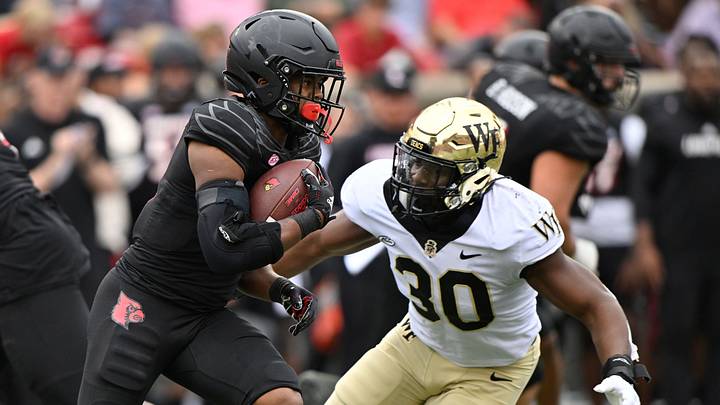 Oct 29, 2022; Louisville, Kentucky, USA;  Louisville Cardinals running back Trevion Cooley (23) runs the ball against Wake Forest Demon Deacons defensive lineman Jasheen Davis (30) during the first half at Cardinal Stadium. Louisville defeated Wake Forest 48-21. Mandatory Credit: Jamie Rhodes-USA TODAY Sports