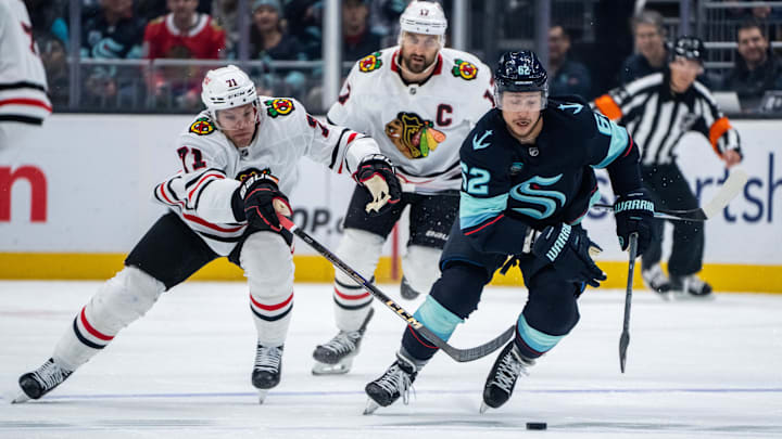 Nov 14, 2024; Seattle, Washington, USA;  Seattle Kraken defenseman Brandon Montour (62) skates against Chicago Blackhawks forward Taylor Hall (71) and forward Nick Foligno (17) during the first period at Climate Pledge Arena. Mandatory Credit: Stephen Brashear-Imagn Images