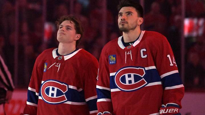 Apr 7, 2026; Montreal, Quebec, CAN; Montreal Canadiens forward Cole Caufield (13) and teammate forward Nick Suzuki (14) during the National Anthem before the game against the Florida Panthers at the Bell Centre. Mandatory Credit: Eric Bolte-Imagn Images