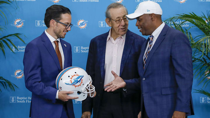 Miami Dolphins head coach Mike McDaniel, shakes hands with general manager Chris Grier and owner Stephen M. Ross after a press conference at Baptist Health Training Center in 2022. Miami Dolphins head coach Mike McDaniel, shakes hands with general manager Chris Grier and owner Stephen M. Ross after a press conference at Baptist Health Training Center in 2022.