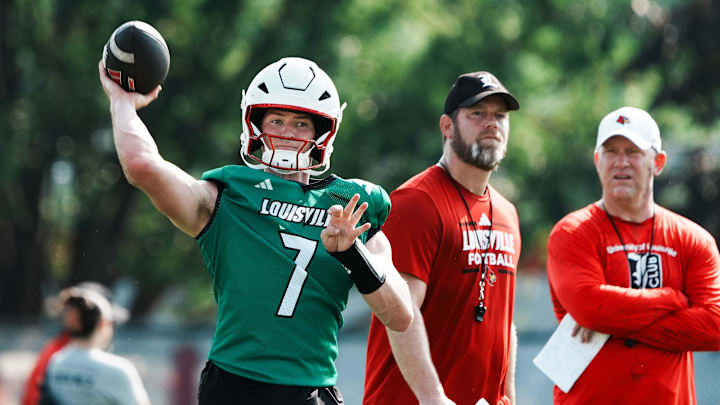 U of L QB Miller Moss (7) passes during practice as OC Brian Brohm and head coach Jeff Brohm, right, watch on the practice field at Cardinal Stadium in Louisville, Ky. on July 30, 2025.
