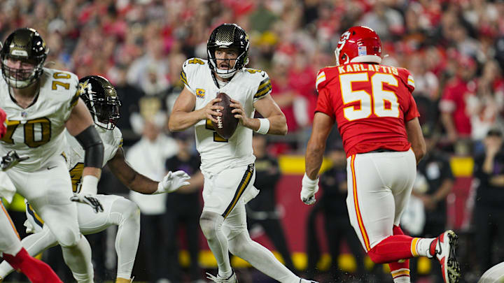 Oct 7, 2024; Kansas City, Missouri, USA; New Orleans Saints quarterback Derek Carr (4) scrambles form Kansas City Chiefs defensive end George Karlaftis (56) during the first half at GEHA Field at Arrowhead Stadium. Mandatory Credit: Jay Biggerstaff-Imagn Images