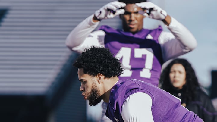 Caleb Presley works with a trainer during a 2023 UW fall practice while Anthony James (47) goes through his rehab.