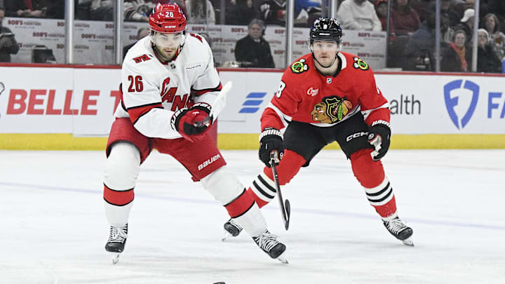 Jan 20, 2025; Chicago, Illinois, USA;  Carolina Hurricanes defenseman Sean Walker (26) moves the puck against Chicago Blackhawks center Ryan Donato (8) during the first period at the United Center. Mandatory Credit: Matt Marton-Imagn Images