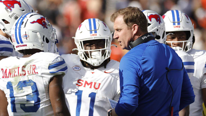 Nov 23, 2024; Charlottesville, Virginia, USA; Southern Methodist Mustangs head coach Rhett Lashlee (center) huddles with players during a stoppage in play in the first half against the Virginia Cavaliers at Scott Stadium. Mandatory Credit: Amber Searls-Imagn Images Nov 23, 2024; Charlottesville, Virginia, USA; Southern Methodist Mustangs head coach Rhett Lashlee (center) huddles with players during a stoppage in play in the first half against the Virginia Cavaliers at Scott Stadium. Mandatory Credit: Amber Searls-Imagn Images