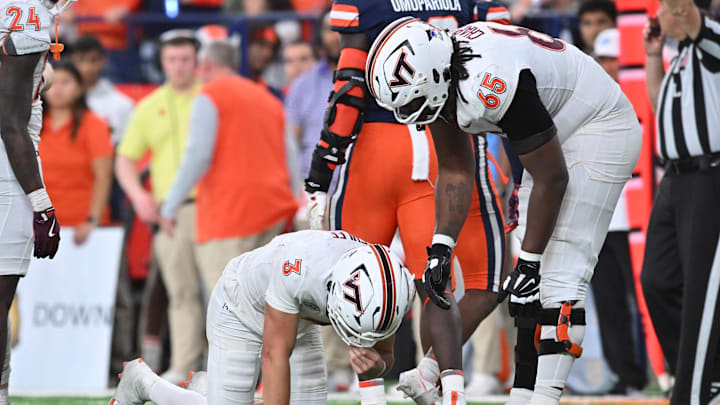 Nov 2, 2024; Syracuse, New York, USA; Virginia Tech Hokies offensive lineman Xavier Chaplin (65) looks after quarterback Collin Schlee (3) who was shaken up on a play against the Syracuse Orange in the fourth quarter at JMA Wireless Dome. Mandatory Credit: Mark Konezny-Imagn Images