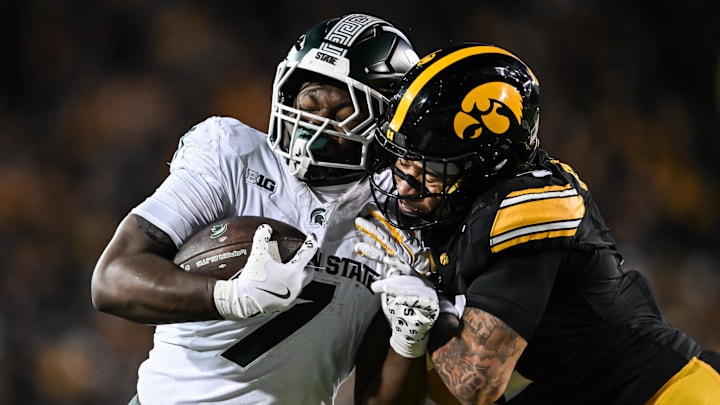 Nov 22, 2025; Iowa City, Iowa, USA; Michigan State Spartans running back Brandon Tullis (7) runs for yards after the catch as Iowa Hawkeyes defensive back Koen Entringer (4) makes the tackle during the third quarter at Kinnick Stadium. Mandatory Credit: Jeffrey Becker-Imagn Images