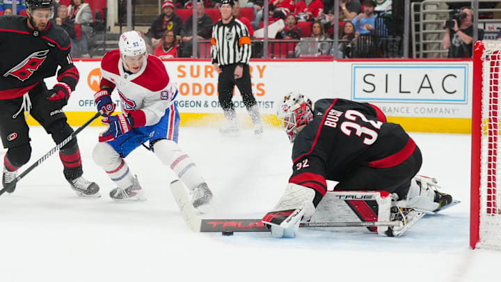 Jan 1, 2026; Raleigh, North Carolina, USA;  Carolina Hurricanes goaltender Brandon Bussi (32) turns the shot away from MontrÈal Canadiens right wing Ivan Demidov (93) during the second period at Lenovo Center. Mandatory Credit: James Guillory-Imagn Images