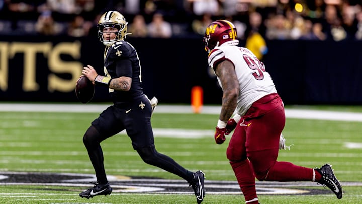 Dec 15, 2024; New Orleans, Louisiana, USA;  New Orleans Saints quarterback Spencer Rattler (18) scrambles against Washington Commanders defensive tackle Daron Payne (94) during the second half at Caesars Superdome. Mandatory Credit: Stephen Lew-Imagn Images