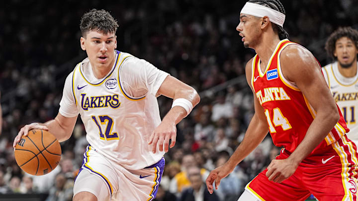 Nov 8, 2025; Atlanta, Georgia, USA; Los Angeles Lakers forward Jake LaRavia (12) dribbles against Atlanta Hawks forward Asa Newell (14) during the first half at State Farm Arena. Mandatory Credit: Dale Zanine-Imagn Images